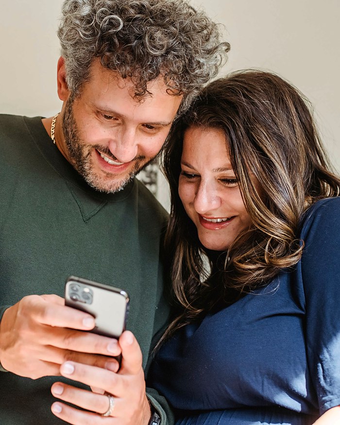 Una coppia sorridente legge un messaggio sul telefono