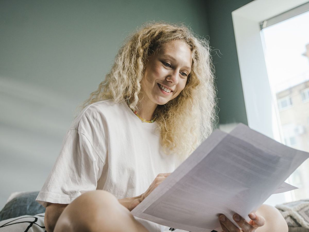 Una donna legge con calma un documento, sorridendo