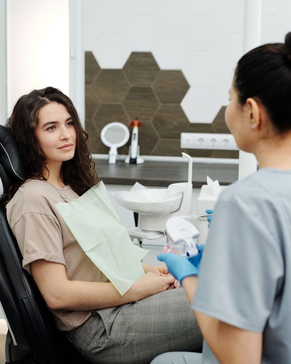Una paziente sulla poltrona parla con la dentista in uno studio moderno